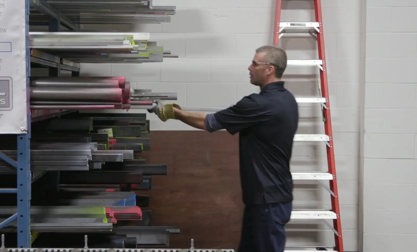 Worker selecting structural steel stock from a warehouse rack