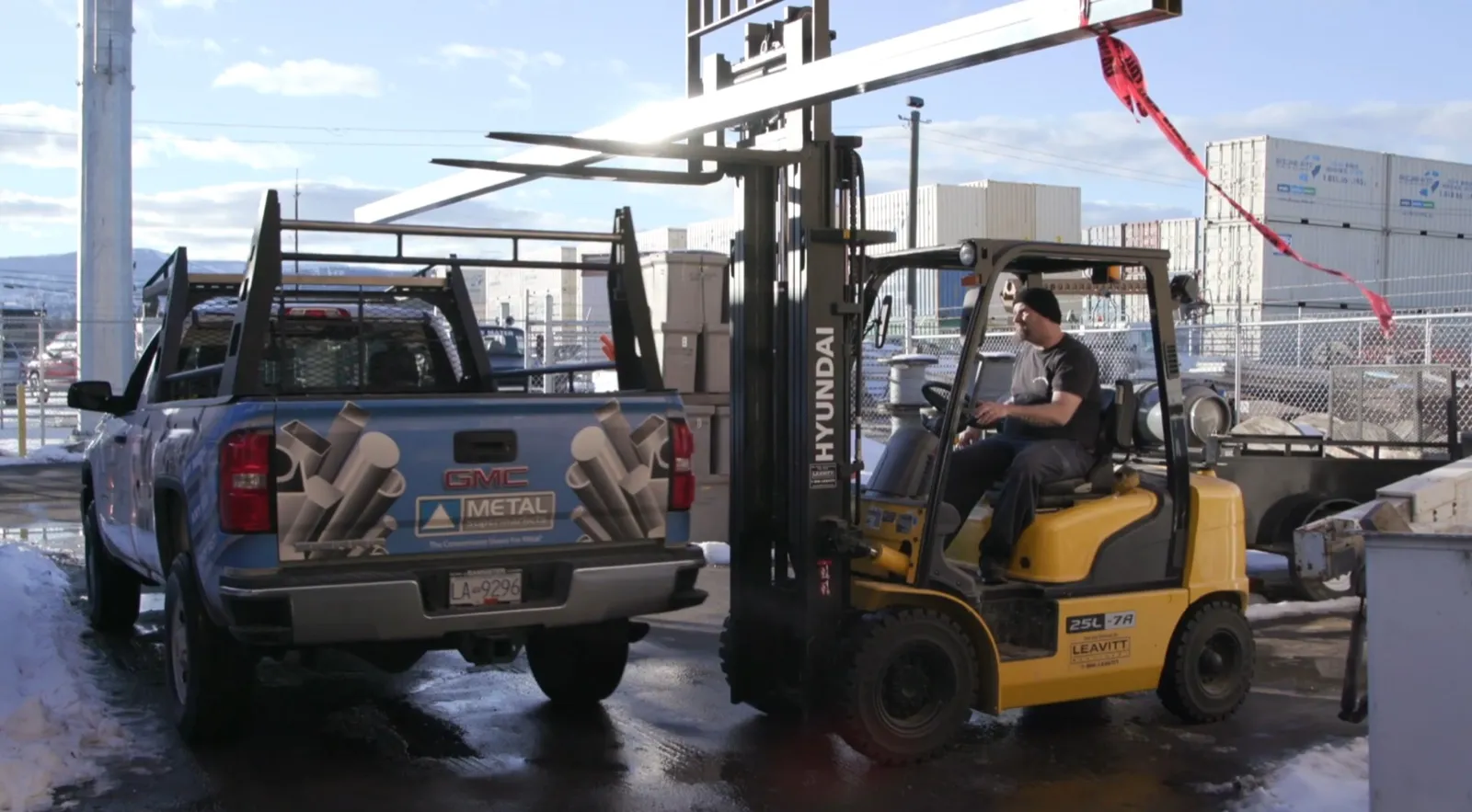 Forklift loading structural steel onto a metal supplier truck