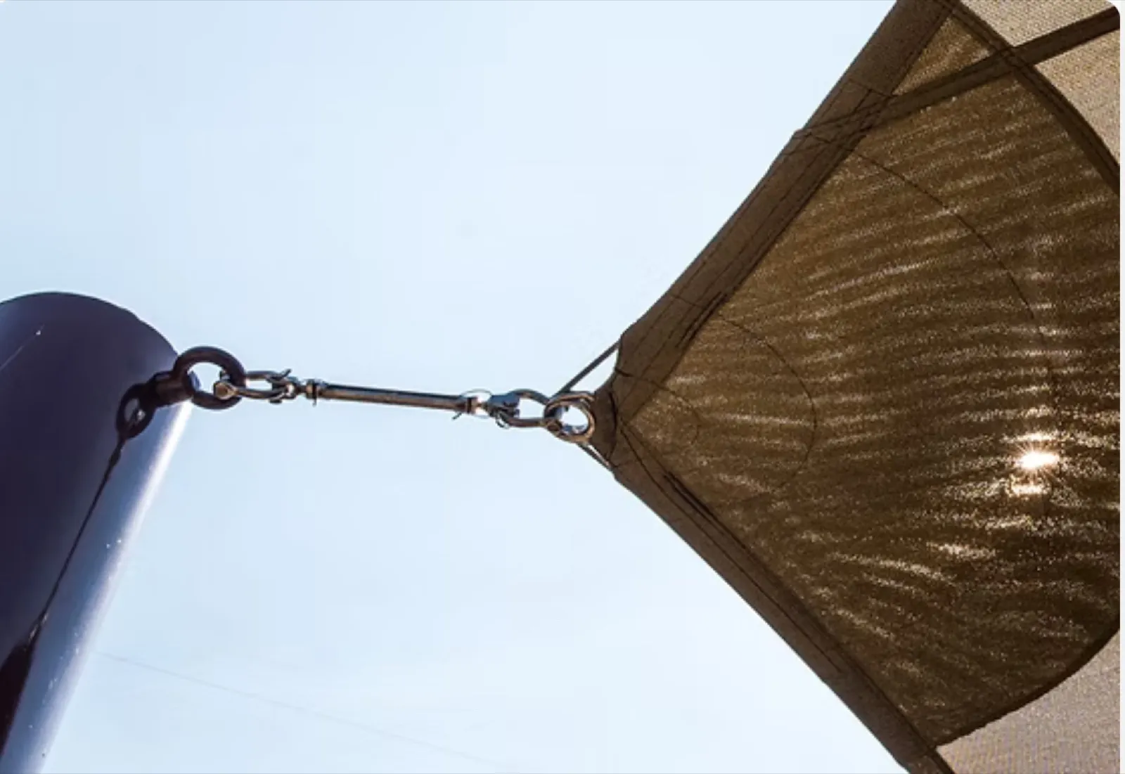 Stainless steel turnbuckle and shackle tensioning a shade sail corner against the sky