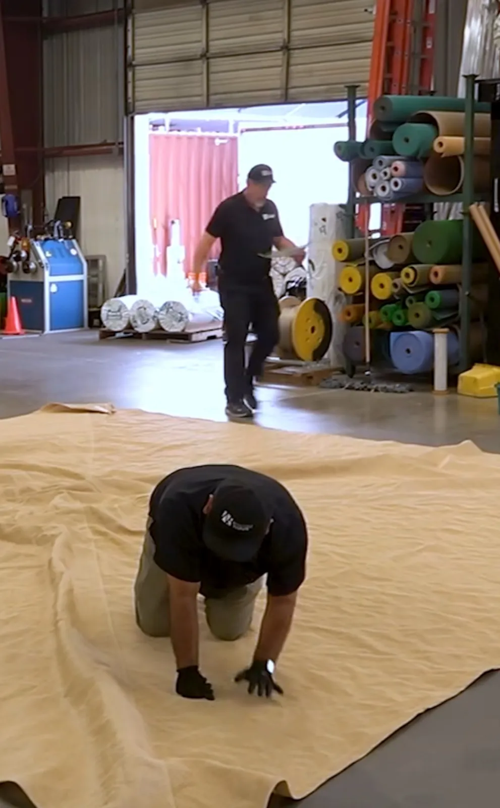 Fabricator laying out a large shade sail panel on the shop floor