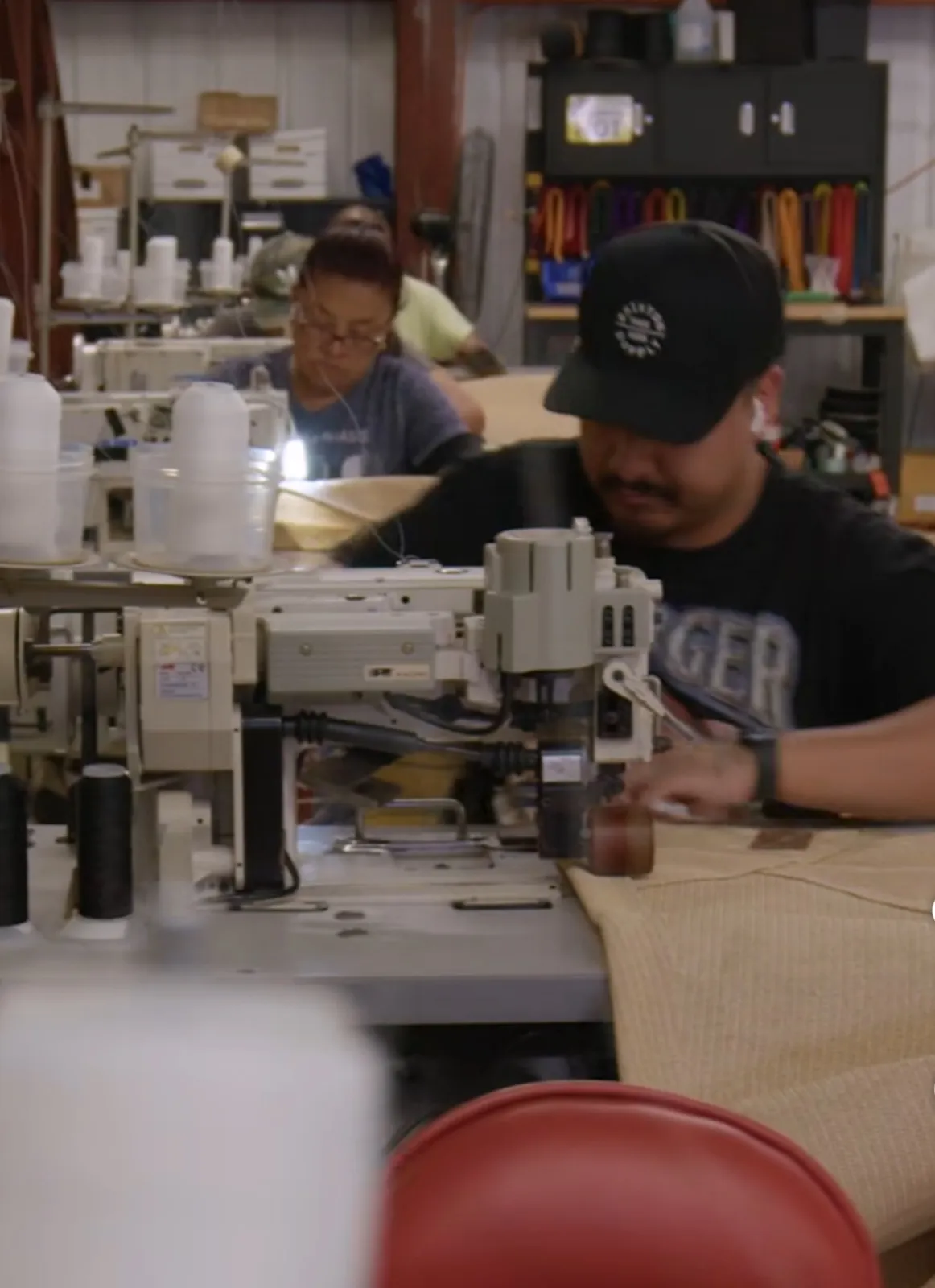 Worker stitching shade sail fabric at an industrial sewing machine